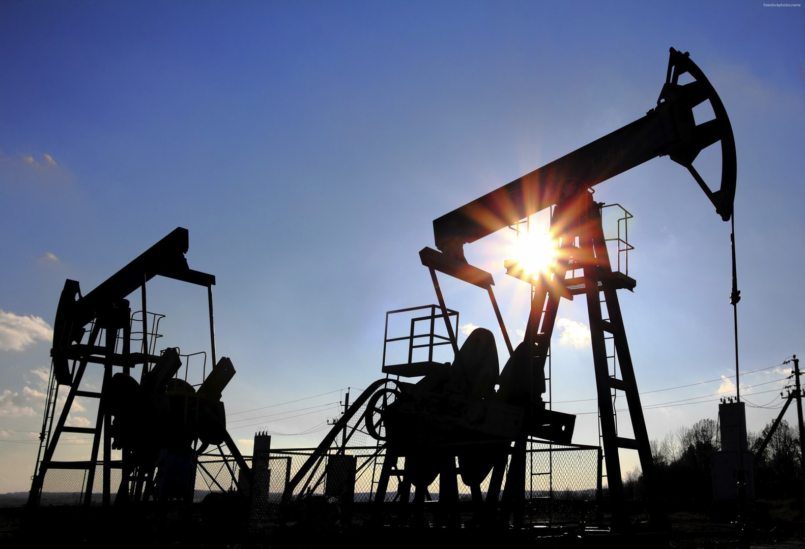 Oil pump jacks silhouette against dramatic sky